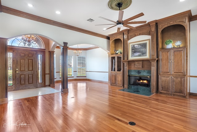 entrance foyer featuring crown molding, arched walkways, ceiling fan with notable chandelier, decorative columns, and visible vents