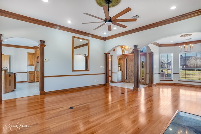 unfurnished living room with decorative columns, visible vents, arched walkways, ceiling fan with notable chandelier, and light wood-style floors