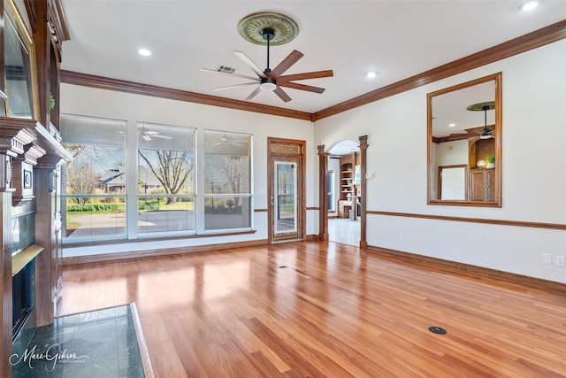 unfurnished living room featuring ceiling fan, ornamental molding, wood finished floors, and a high end fireplace