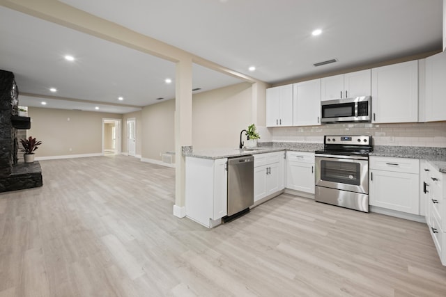 kitchen with backsplash, stainless steel appliances, light stone countertops, and baseboards