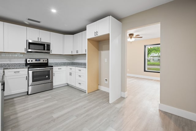 kitchen with visible vents, light stone countertops, light wood-style flooring, backsplash, and stainless steel appliances
