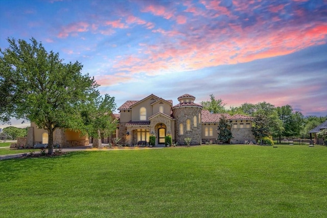 mediterranean / spanish-style home with a yard, a tile roof, stone siding, and stucco siding