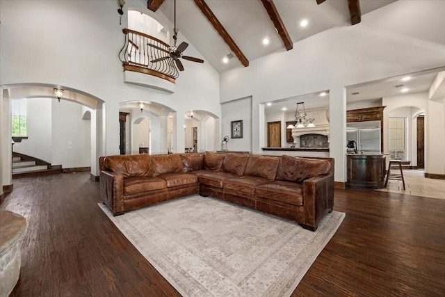 living area featuring arched walkways, a ceiling fan, wood finished floors, and high vaulted ceiling