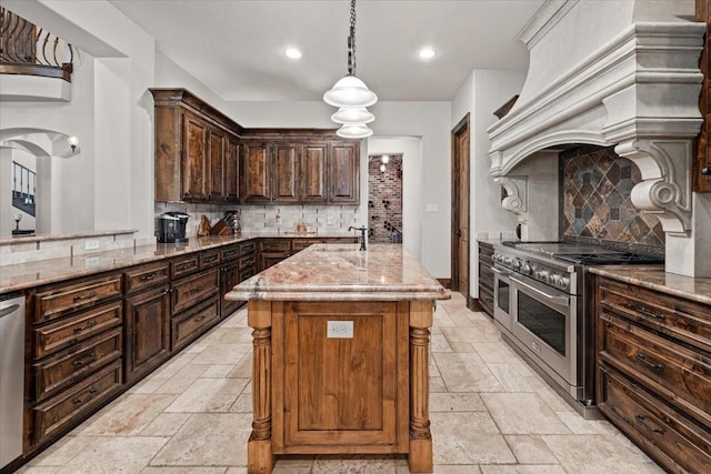 kitchen featuring light stone counters, backsplash, stainless steel appliances, and stone tile floors