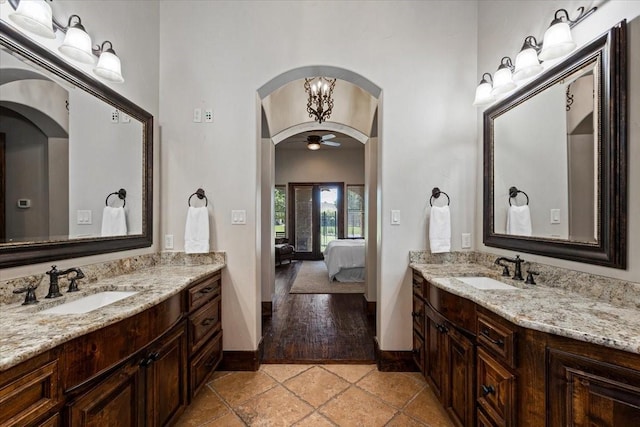 bathroom featuring a sink, baseboards, ensuite bathroom, and two vanities