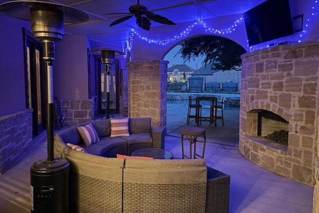 view of patio featuring a ceiling fan and an outdoor living space with a fireplace