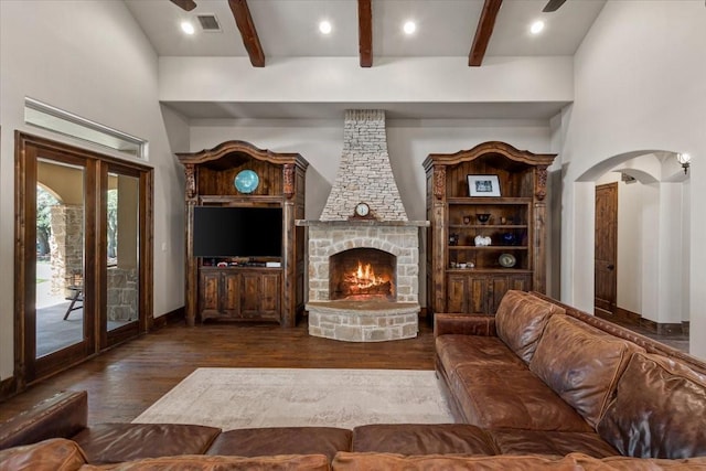 living area with visible vents, arched walkways, wood finished floors, and beam ceiling