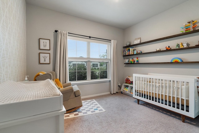 carpeted bedroom with baseboards and a nursery area