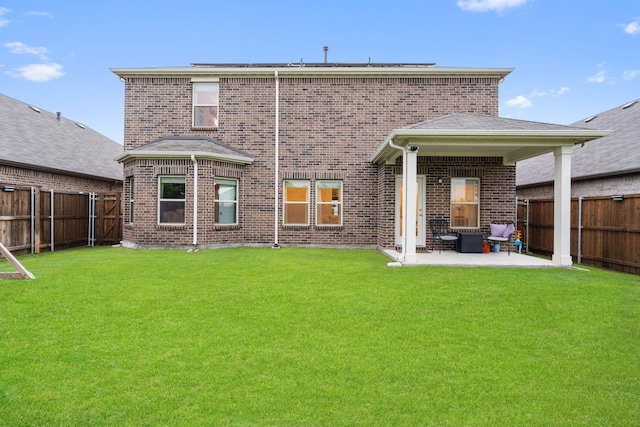 rear view of property with brick siding, a fenced backyard, and a patio area