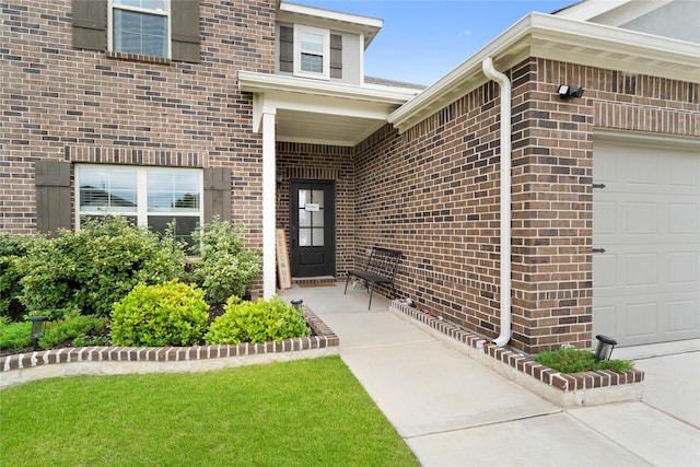 entrance to property featuring an attached garage and brick siding
