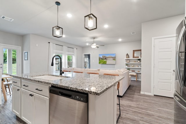 kitchen with visible vents, a ceiling fan, a sink, light wood finished floors, and stainless steel appliances