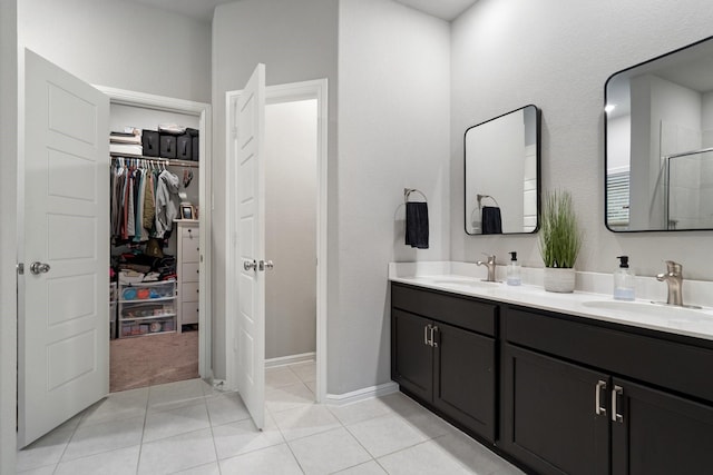 bathroom with double vanity, a sink, tile patterned floors, and a spacious closet