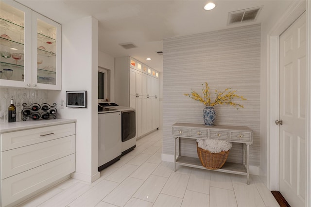 7449 Tophill Ln, Dallas, TX 75248 - kitchen featuring washing machine and clothes dryer, white cabinets, light countertops, recessed lighting, and glass insert cabinets