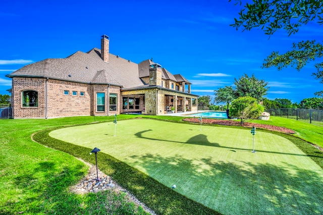 7101 Royal Birkdale Dr, Cleburne, TX 76033 - rear view of property with an area to practice putting, brick siding, a chimney, and a patio area