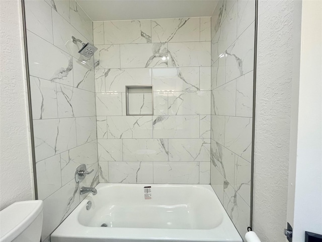 full bathroom featuring toilet, a textured wall, and shower / bath combination