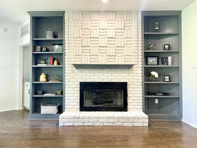 unfurnished living room featuring baseboards, a fireplace, built in shelves, and wood finished floors
