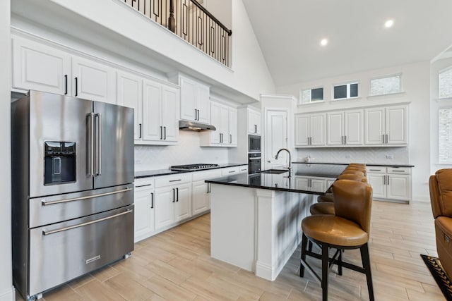 1520 Rough Rider Ct, Celina, TX 75009 - kitchen featuring a sink, dark countertops, white cabinets, under cabinet range hood, and appliances with stainless steel finishes
