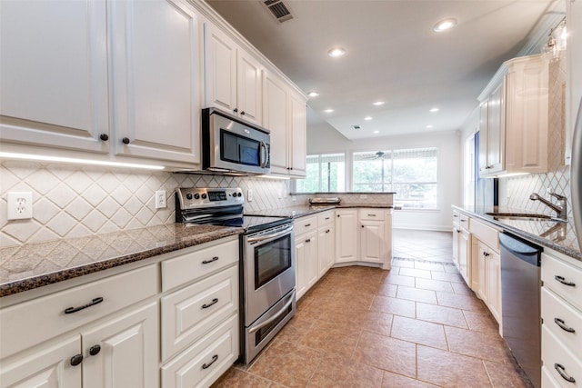 kitchen featuring decorative backsplash, visible vents, a sink, dark stone counters, and stainless steel appliances
