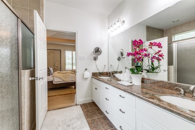 ensuite bathroom featuring connected bathroom, tile patterned floors, a shower stall, and a sink