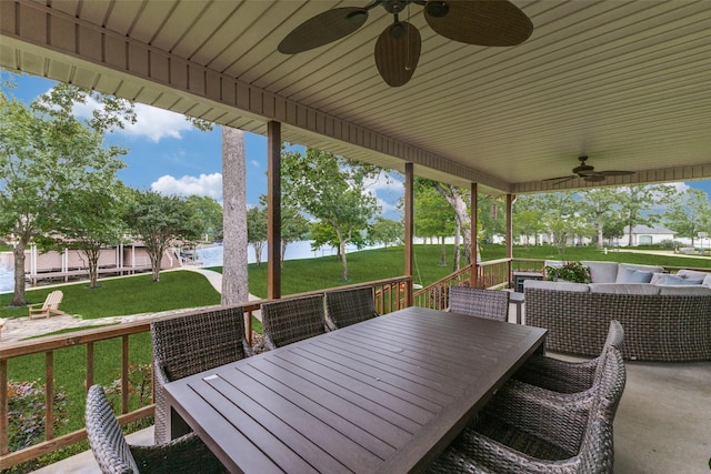 deck featuring a yard, a water view, ceiling fan, and outdoor dining space
