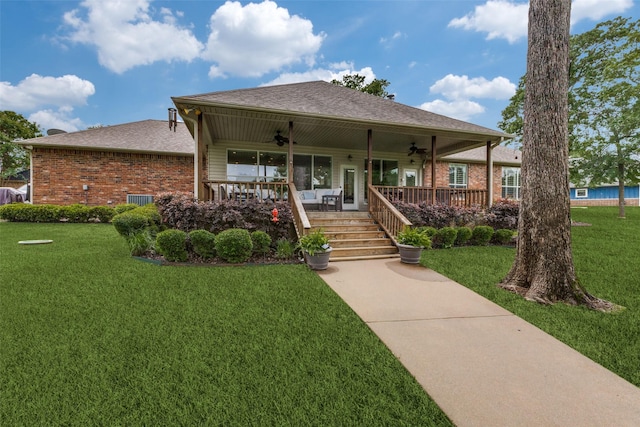view of front facade with a shingled roof, ceiling fan, a front lawn, and brick siding