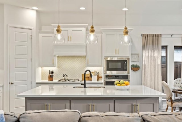 kitchen with light countertops, stainless steel appliances, decorative backsplash, and a sink