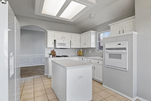 61 Sonora Dr, Trophy Club, TX 76262 - kitchen featuring a kitchen island, arched walkways, light countertops, a sink, and white appliances