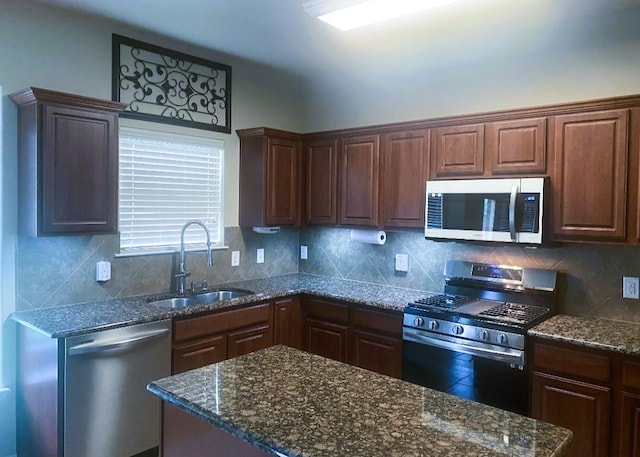 kitchen with dark stone counters, stainless steel appliances, a sink, and tasteful backsplash