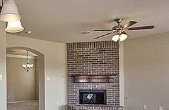 unfurnished living room featuring baseboards, arched walkways, a ceiling fan, and a fireplace