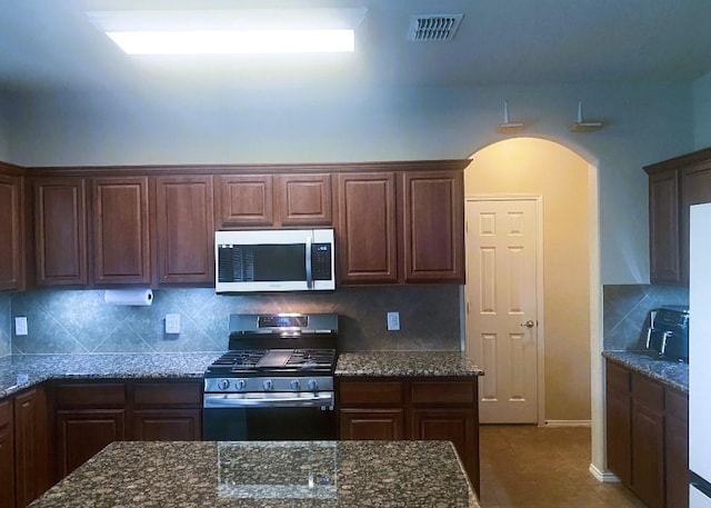 3117 Burwood Ln, Royse City, TX 75189 - kitchen with stainless steel appliances, arched walkways, tile patterned floors, and dark stone countertops