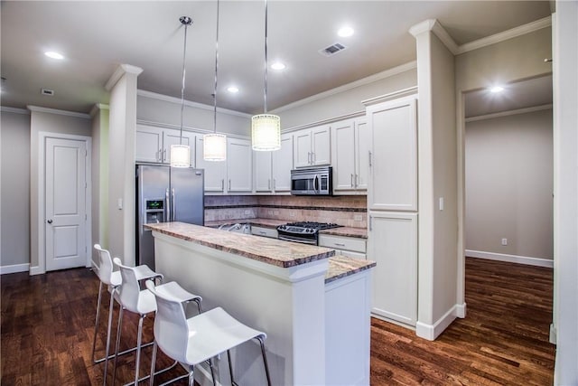 kitchen with visible vents, a breakfast bar, dark wood-style floors, a center island, and appliances with stainless steel finishes