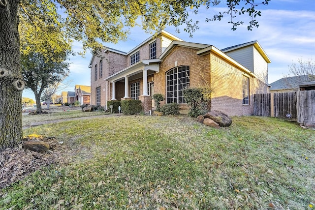 view of front of home with fence, a front lawn, and brick siding