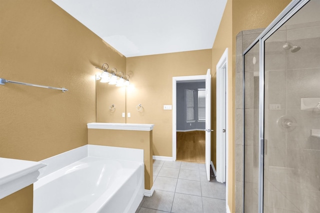 bathroom featuring tile patterned flooring, vanity, baseboards, a bath, and a shower stall