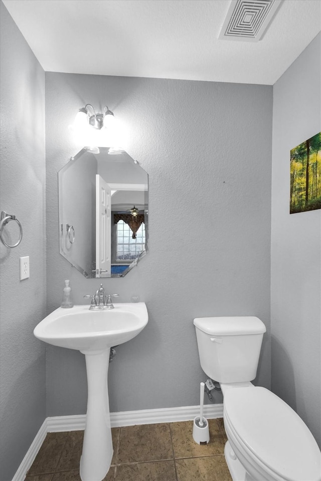half bathroom with visible vents, baseboards, tile patterned floors, and toilet