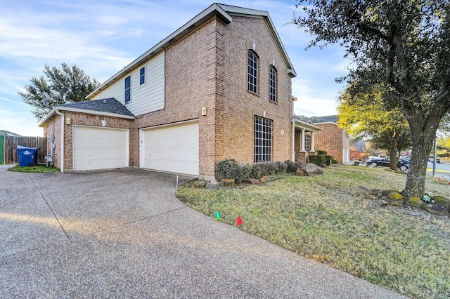 view of home's exterior featuring concrete driveway, brick siding, an attached garage, and fence