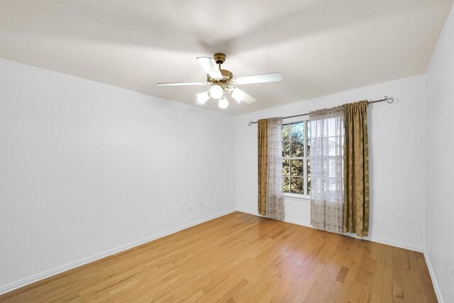 spare room featuring baseboards, ceiling fan, and light wood finished floors