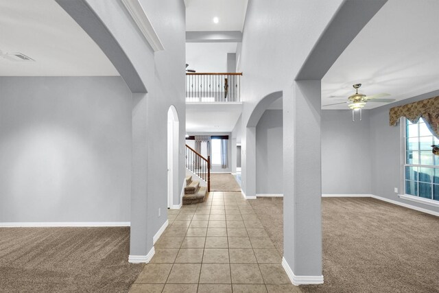 entryway featuring arched walkways, a ceiling fan, baseboards, and carpet