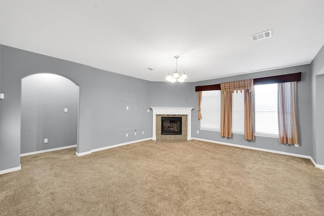 unfurnished living room with arched walkways, a notable chandelier, visible vents, and carpet