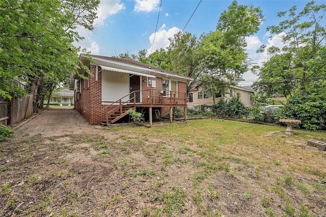 back of house with brick siding, a lawn, fence, and stairway