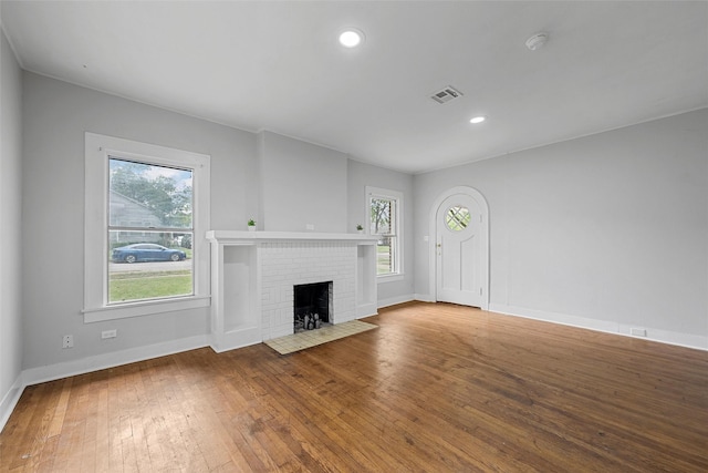 unfurnished living room featuring wood-type flooring, baseboards, visible vents, and a fireplace