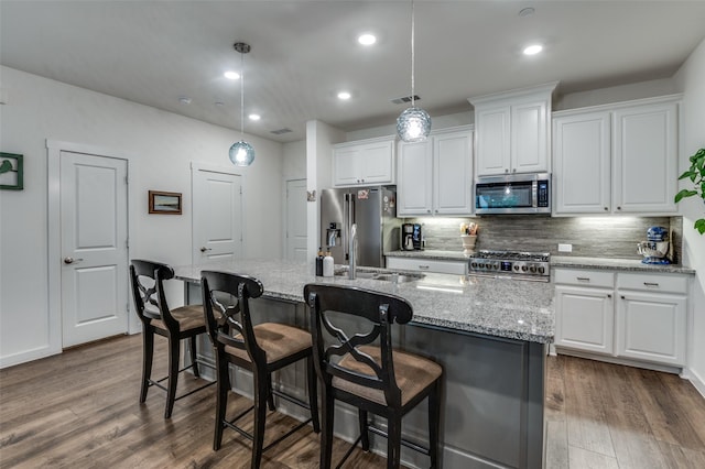 kitchen with appliances with stainless steel finishes, white cabinets, backsplash, and dark wood finished floors