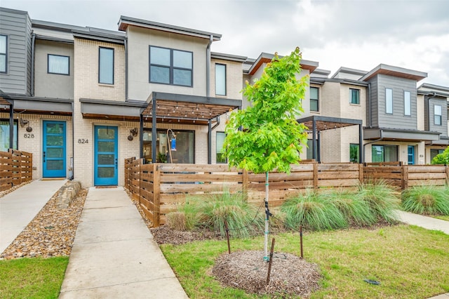 townhome / multi-family property with brick siding, fence, and stucco siding