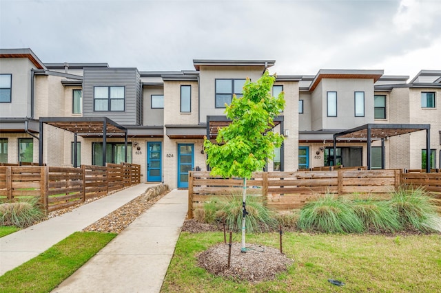 townhome / multi-family property with brick siding and a fenced front yard