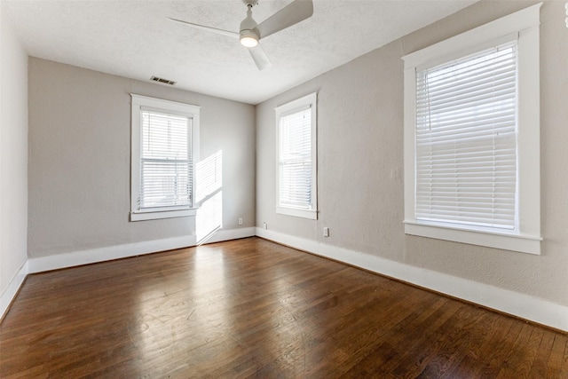 empty room with baseboards, ceiling fan, visible vents, and wood finished floors