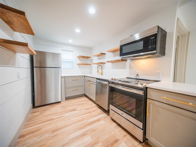 kitchen featuring stainless steel appliances, open shelves, gray cabinetry, and light wood-type flooring