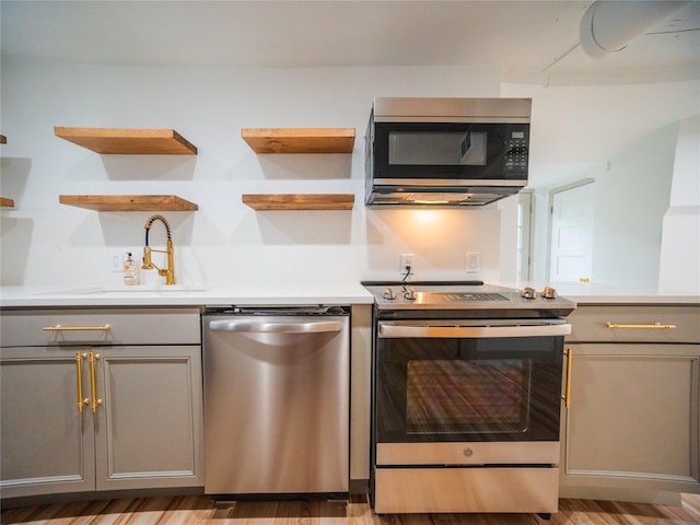 kitchen with open shelves, a sink, gray cabinetry, and stainless steel appliances