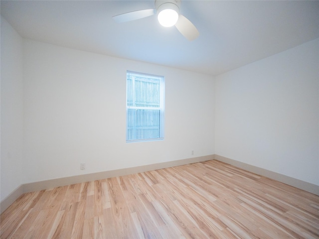 spare room with baseboards, ceiling fan, and wood finished floors