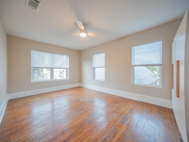 unfurnished room with visible vents, wood-type flooring, ceiling fan, and baseboards