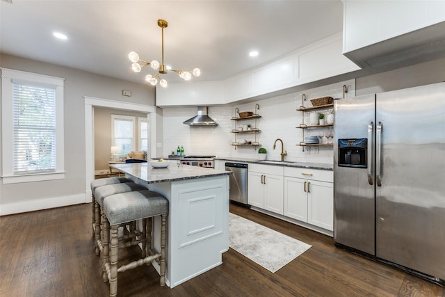 kitchen featuring decorative backsplash, wall chimney exhaust hood, white cabinetry, a sink, and appliances with stainless steel finishes