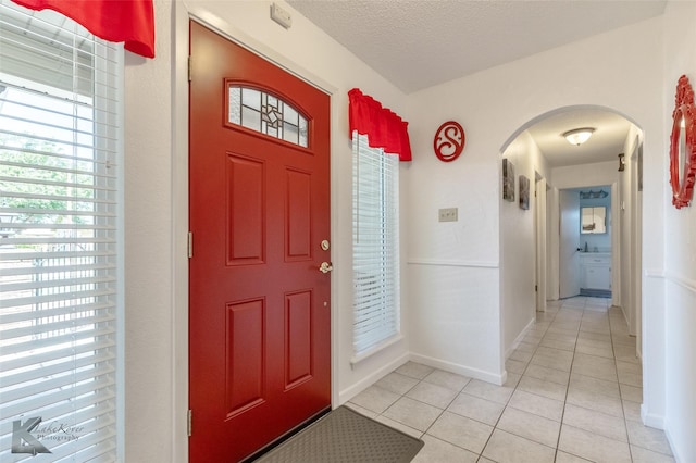 5631 Southmoor Dr, Abilene, TX 79606 - foyer entrance with light tile patterned floors, arched walkways, baseboards, and a textured ceiling